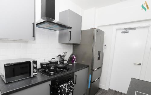 a kitchen with a microwave and a stove top oven at Essex Lodge - TSAC in Middlesbrough