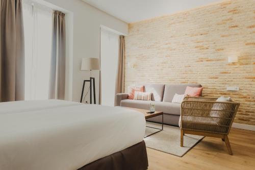 a hotel room with a bed and a couch at Aquitania Home Suites in Seville