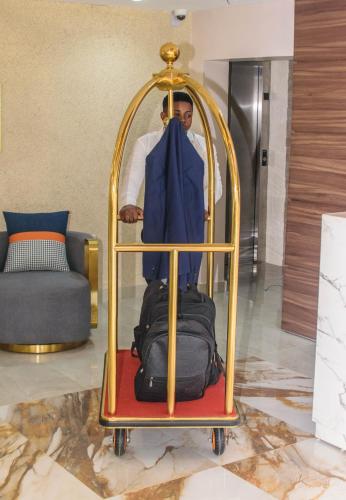 a man standing next to a luggage rack in a room at Blue Orange Hotel and Towers in Shomolu