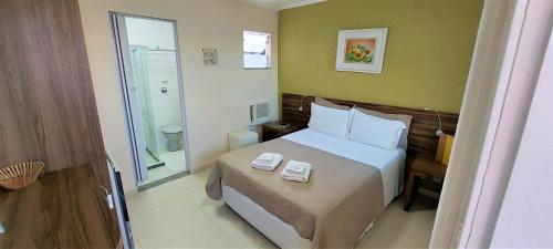 a bedroom with a bed with two towels on it at Pousada Mariá in Cabo Frio