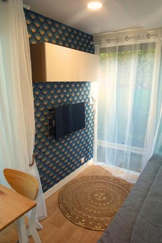 un salon avec une télévision à écran plat sur un mur dans l'établissement La Promenade des 2 Pins - Chic, à Poisat