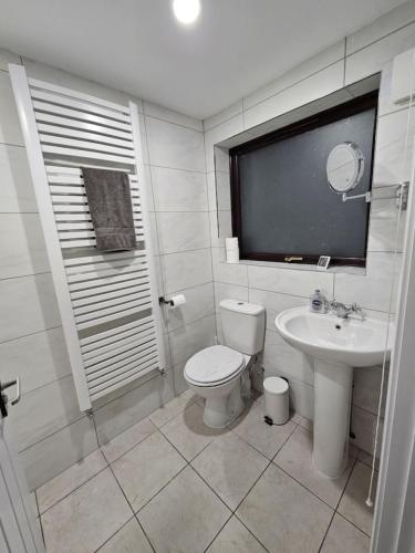 a white bathroom with a toilet and a sink at 3BR, 6 min to central station, full kitchen in Saint Helens