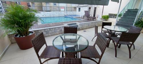 a patio with a table and chairs and a swimming pool at Pousada Mariá in Cabo Frio