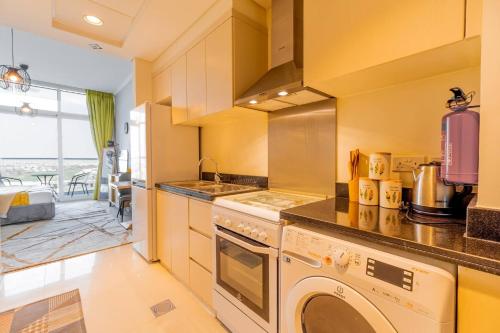 a kitchen with a stove and a washer and dryer at Elegant Studio in Damac Hills - Exclusive Living with Premium Amenities, Managed by Think Realty in Dubai