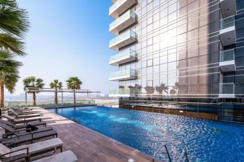 an exterior view of a building with a swimming pool at Elegant Studio in Damac Hills - Exclusive Living with Premium Amenities, Managed by Think Realty in Dubai