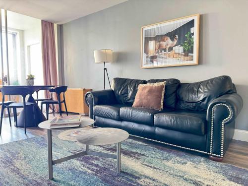 a living room with a black leather couch and a table at Atlanta Downtown! High Rise! Onsite Parking LM609 in Atlanta