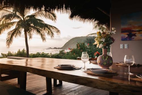 a table with plates and wine glasses and a palm tree at Casa Playa Verde - 200Mbps Wifi in Troncones