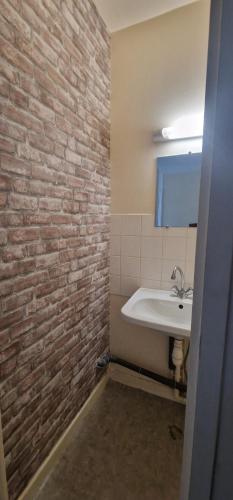a bathroom with a white sink and a brick wall at L'espérance in Felletin