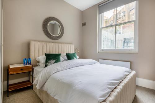 a bedroom with a bed with a mirror and a window at Hampstead High Flyer in London