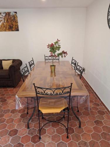 une table en bois avec des chaises et un vase avec des fleurs. dans l'établissement La maison d'Antoine à Robion, à Robion