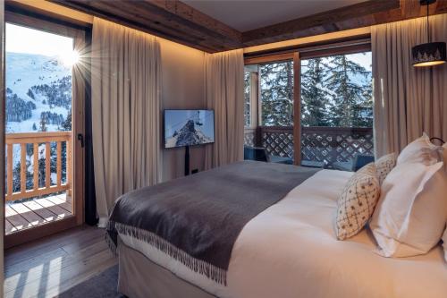 une chambre avec un grand lit et un balcon dans l'établissement Antarès ORION 102 - Ski inski out apartment, à Méribel