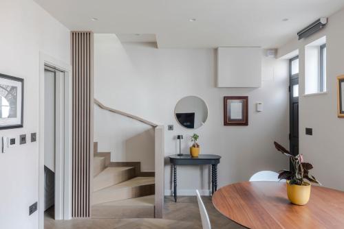 a dining room with a table and a staircase at Stunning 2-Bed Mews House with AC near Regent's Park in London