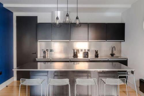 eine Küche mit einer Theke und Hockern aus Edelstahl in der Unterkunft The Socialite - Covent Garden - by Frankie Says in London