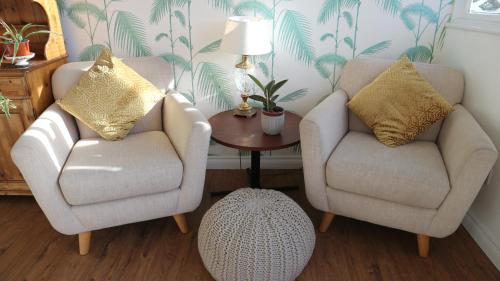a living room with two chairs and a table at Peterborough House in Saint Aubin