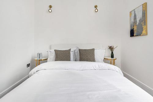 a white bedroom with a large white bed with pillows at Lady on the Lane- 2 bed Primrose Hill in London