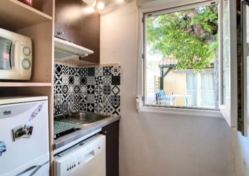 une petite cuisine avec un évier et une fenêtre dans l'établissement Villa Maëlyssia - Les villas du lac, à Soustons