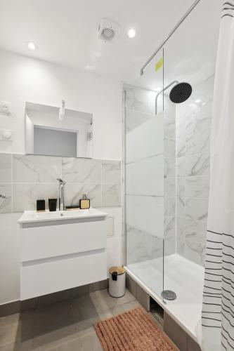 une salle de bain blanche avec un lavabo et une douche dans l'établissement Chic and spacious apart with parking, à Colombes