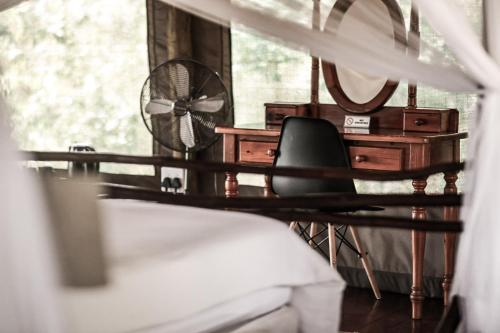 a bedroom with a bed and a fan and a window at Muweti Bush Lodge in Grietjie Nature Reserve