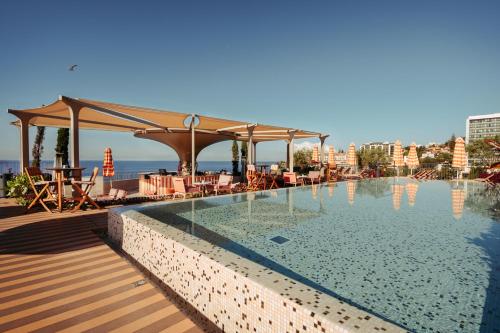 a swimming pool with a table and a pavilion at NEXT - by Savoy Signature in Funchal