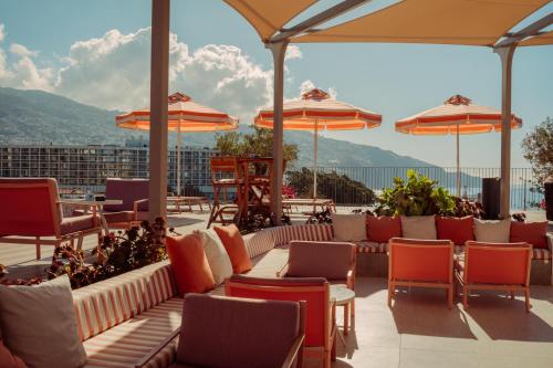 a patio with chairs and tables and umbrellas at NEXT - by Savoy Signature in Funchal