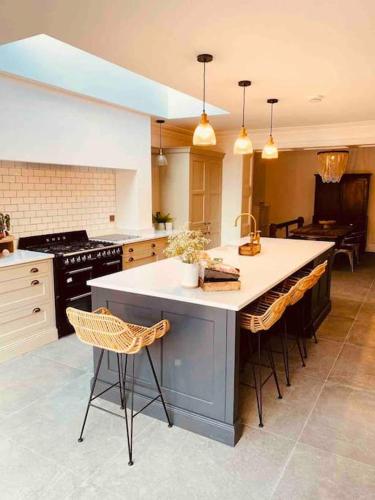 a kitchen with a large island with a sink and chairs at Edwardian house by the seaside in Porthcawl