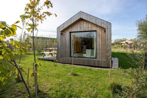 a small house in a garden with a large window at Hello Zeeland - Zeeuwse Liefde Tiny House 3 in Westkapelle