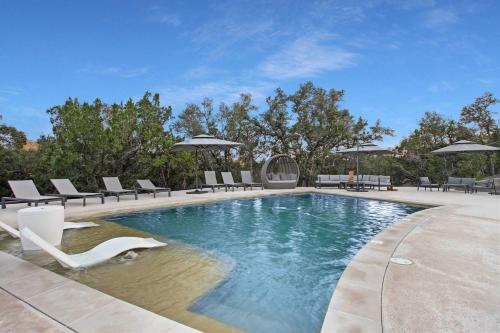 a swimming pool with lounge chairs at Starlight Horizon Cabin H - Pet-Friendly Texas Hill Country Cabin Near Canyon Lake - Pool, Stargazing & Group Getaways - Sleeps 8 in Canyon Lake