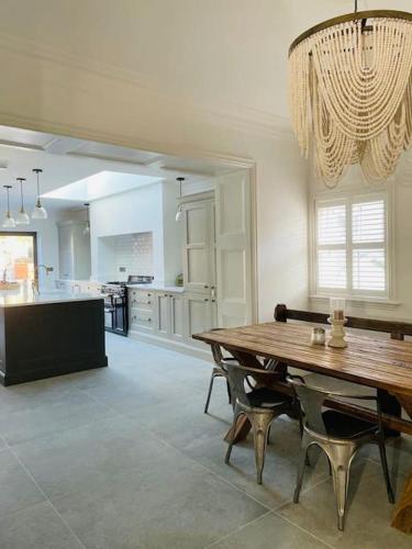 a dining room with a table and a kitchen at Edwardian house by the seaside in Porthcawl