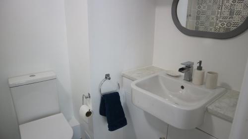 a white bathroom with a sink and a toilet at Peterborough House in Saint Aubin