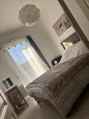 une chambre avec un lit et une grande fenêtre dans l'établissement Logement cosy en bord de mer et étang, à Sète