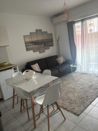 un salon avec une table et des chaises blanches dans l'établissement Logement cosy en bord de mer et étang, à Sète