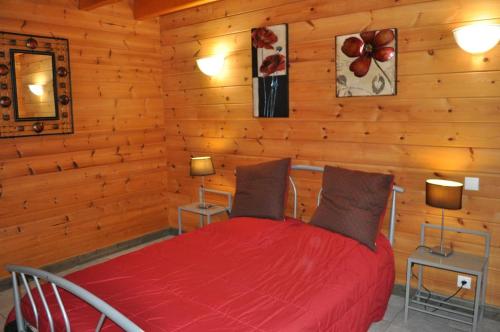 - une chambre avec un lit rouge dans une cabane en rondins dans l'établissement Chalet Maya, Belle vue lac, Sauna, SPA et Wifi, à Gérardmer