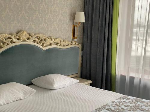 a bedroom with a bed with a headboard and a window at Royal Olympic Hotel in Kyiv