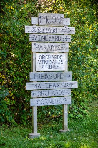 a directional sign with names on it in the grass at Old Orchard Inn in Wolfville