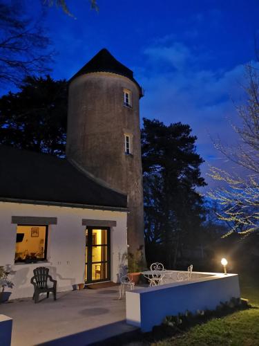 a building with a clock tower at night at Le moulin de La Retardière in Orvault