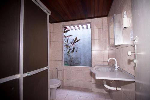 un bagno con lavandino, water e finestra di Casa aconchegante a Natal