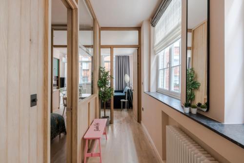 - un couloir avec tabouret rose dans une chambre avec fenêtres dans l'établissement Soho Swank - by Frankie Says, à Londres