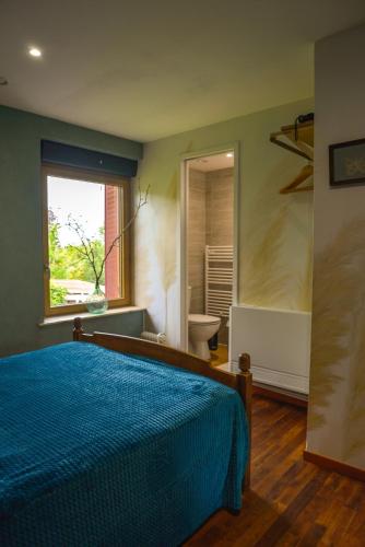 - une chambre avec un lit bleu et une salle de bains dans l'établissement Espace Spirituel, à Saint-Sulpice-le-Dunois