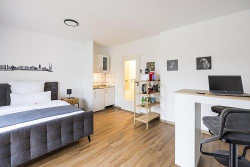 a bedroom with a bed and a desk with a laptop at CityWest Apartment - mit Balkon in Bielefeld