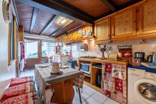 une cuisine avec une table et une machine à laver dans l'établissement Aux 4 saisons, à Le Bouchet-Mont Charvin