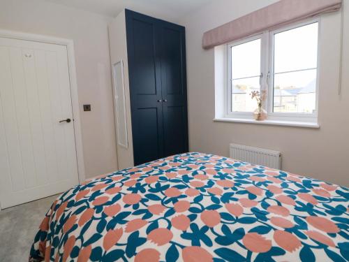 a bedroom with a bed with a blue cabinet and two windows at Knoll View in Bradwell
