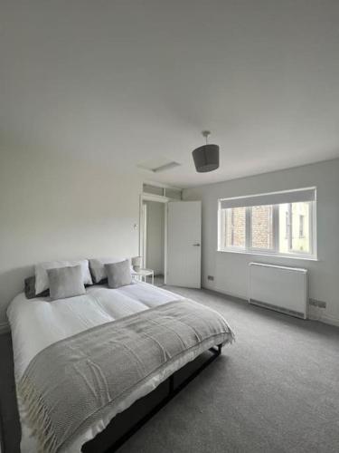 a white bedroom with a large bed and a window at Cromer Coastal Cottage in Cromer