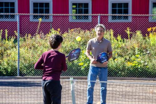 two young men playing tennis on a tennis court at Old Orchard Inn in Wolfville