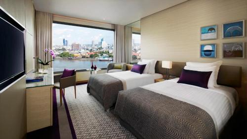 a hotel room with two beds and a large window at Avani Plus Riverside Bangkok Hotel in Bangkok
