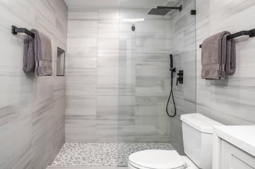 a white bathroom with a toilet and a shower at Deluxe Oceanside Resort Vistas in Kihei