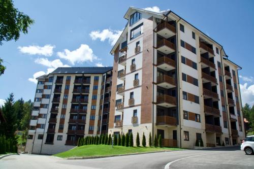 a tall apartment building with a car parked in front at Forest Zlatni Bor in Zlatibor