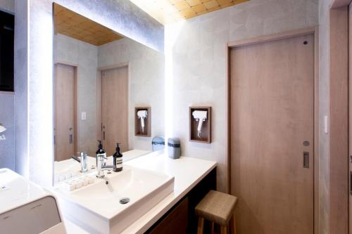 a bathroom with a sink and a mirror at 貸し切り宿 世紡 YOTSUMUGI sakazuki and iyasaka in Yufuin