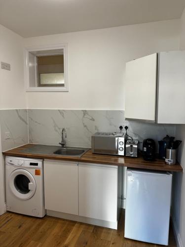 eine Küche mit Spüle und Waschmaschine in der Unterkunft Urban Studio Finchley in Finchley