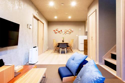 a living room with a blue couch and a table at 貸し切り宿 世紡 YOTSUMUGI sakazuki and iyasaka in Yufuin