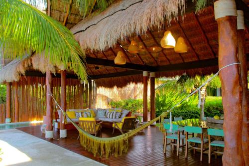 a patio with chairs and tables and a straw umbrella at Lipsos Private Luxury Beachfront home in Progreso